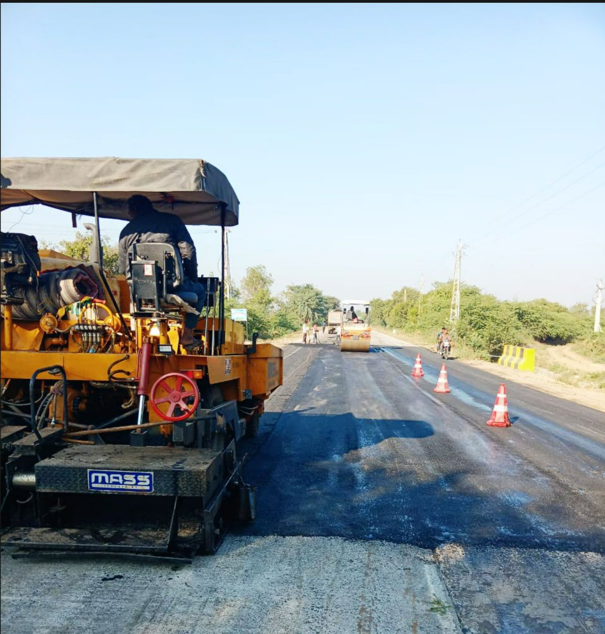 Active highway construction site with specialized paving equipment